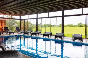 a swimming pool with chairs and a large window at Hotel Kúria Červený Majer in Senec