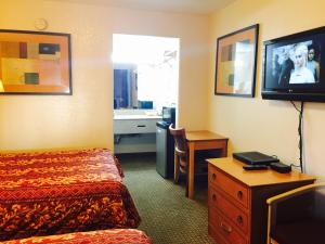 a hotel room with a bed and a desk and a television at Economy Inn in San Francisco