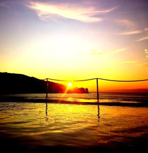 a sunset on the beach with a volleyball net at Beach house BellaVista with hot pool in Trogir