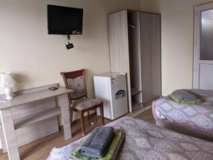 a room with a bed and a desk and a television at Гостевой Дом В Гостях на Иссык-Куле in Cholpon-Ata
