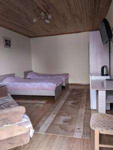 a room with two beds and a table in it at Гостевой Дом В Гостях на Иссык-Куле in Cholpon-Ata