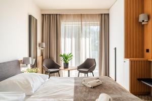 a hotel room with a bed and chairs and a window at Akces Medical Fit & Spa in Dźwirzyno +25 photos