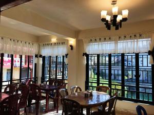 a restaurant with tables and chairs and large windows at Gracious Lodge in Shillong