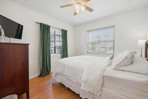 a white bedroom with a bed and a flat screen tv at Walkable Duplex Near Forsyth Park in Savannah