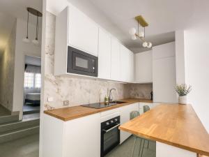 a kitchen with white cabinets and a wooden counter top at Infinity Ocean View Suite in Adeje