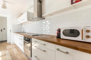 a kitchen with white cabinets and a microwave at Duplex d'Exception avec Patio Privé - Hyper Centre in Lille