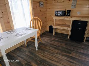 a table and chair in a room with a desk and microwave at Letchworth Valley Campground Cabins in Bliss +17 photos