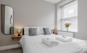 スキップトンにあるCentral Skipton - Devonshire Court Apartmentsの白いベッドとタオルが2枚置かれた寝室