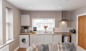 a kitchen with a sink and a washing machine at Central Skipton - Devonshire Court Apartments in Skipton
