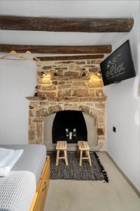a room with a stone fireplace with a bed and two stools at Sitia Sandali elia apartment in Epáno Dhris