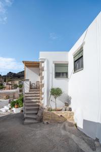 a white house with a staircase next to a building at Sitia Sandali elia apartment in Epáno Dhris