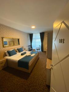 a hotel room with a bed with blue pillows at Hotel Pejton in Prishtinë