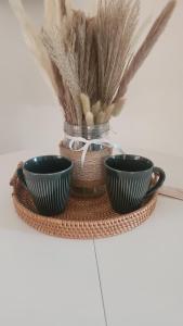 two black cups on a wicker tray with feathers at Love Room Les dessous du Garlaban in Roquevaire +3 photos