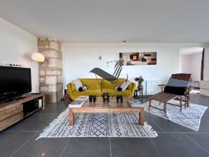 a living room with a yellow couch and a tv at Le Nid Marin - Spacieuse maison avec jardin in Moëze