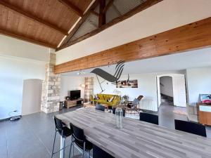 a dining room and living room with a large wooden table at Le Nid Marin - Spacieuse maison avec jardin in Moëze