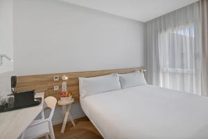 a bedroom with a large white bed and a desk at B&B HOTEL Leiria Fatima in Leiria