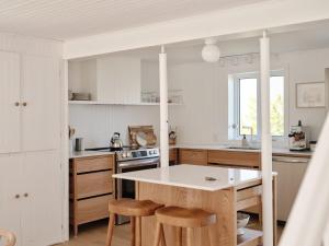 una cocina con armarios blancos, mesa y taburetes en Maison Fleuve - Kamouraska, en Sainte-Hélène-de-Kamouraska