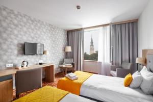Una habitación de hotel con dos camas y un televisor. en Hotel Arche, en Częstochowa