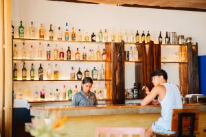 two people sitting at a bar with bottles of alcohol at Ursula Beach Resort in El Nido