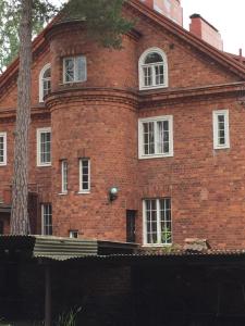 un bâtiment en briques rouges avec des fenêtres blanches et un arbre dans l'établissement Famous Villa Bertel Jung, à Helsinki