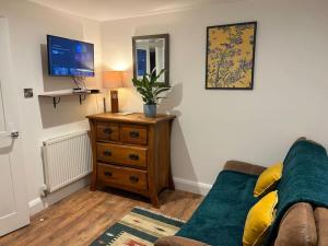 a living room with a couch and a dresser with a tv at Self contained two room studio apartment, own entrance, private parking in Brighton & Hove
