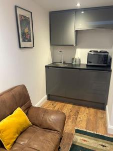 a living room with a couch and a kitchen at Self contained two room studio apartment, own entrance, private parking in Brighton & Hove +20 photos