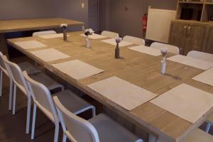 a large wooden table with white chairs around it at Hof Ter Meulen in De Haan
