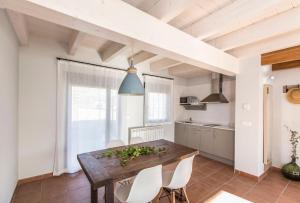 Una cocina con una mesa de madera y sillas blancas. en Senda del Cabrerizo, en Albarracín