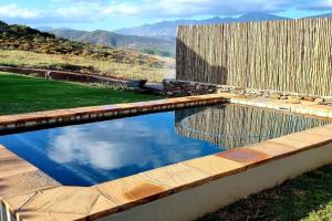 a swimming pool with a fence and mountains in the background at Ammara Farmstay in Bonnievale