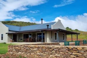 a white house with a stone wall at Ammara Farmstay in Bonnievale