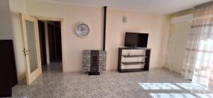 a living room with a television and a clock on the wall at Mara casa vacanza in Maracalagonis