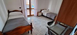 Una pequeña habitación con dos camas y una ventana. en Mara casa vacanza, en Maracalagonis