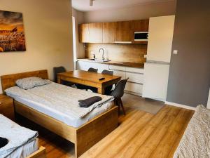 a room with a bed and a table and a kitchen at Noclegi Skorpion in Poddębice
