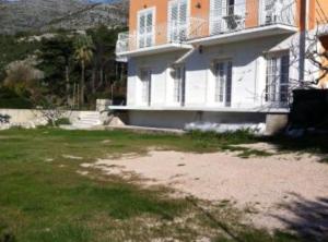 a large white house with a balcony on a yard at Apartments Villa Novak in Slano