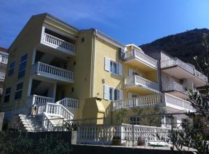 a large yellow building with white balconies on it at Apartments Villa Novak in Slano