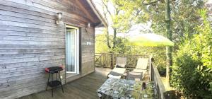 a deck with a table and chairs and an umbrella at Chez fontaine in Lahonce