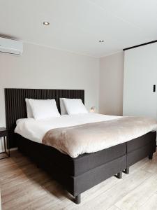 a bedroom with a large bed with white walls at Vakantiehuisje Noé in Gorinchem