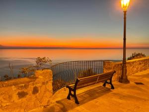 a bench next to a light pole and the ocean at Residenza Matilde in Fiumefreddo Bruzio