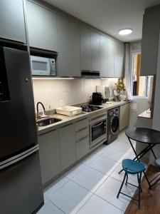 Una cocina con electrodomésticos de acero inoxidable y una mesa. en Home Club em Barra Velha Seu Refúgio à Beira-Mar, en Barra Velha