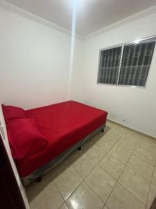 a red bed in a white room with a window at Casa com Piscina individual in Paulista