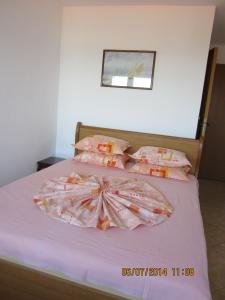 a bedroom with a bed with pink sheets and pillows at Guesthouse Olimp in Sozopol