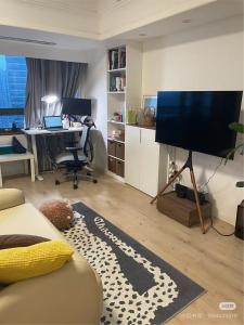 een woonkamer met een bank en een bureau met een televisie bij Luxury Entire 1B flat in ChangNing in Shanghai