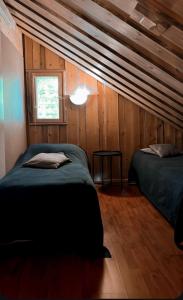 two beds in a room with wooden walls at Kelotulkku Lodge in Muurame