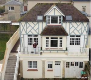 a person standing on the balcony of a white house at Villa Chantereyne entrée de plage, 8 couchages in Ouistreham