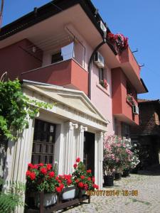 a pink building with red flowers in front of it at Guesthouse Olimp in Sozopol