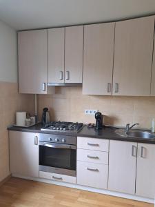 cocina con armarios blancos, fogones y fregadero en Welcoming apartment, en Anykščiai 2 fotos más