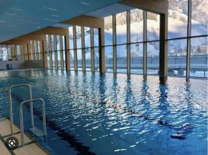 a large swimming pool in a building with windows at Gotthard Hotel Apartment in Andermatt