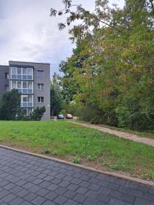 a building and a sidewalk in front of a grass field at Welcoming apartment in Anykščiai