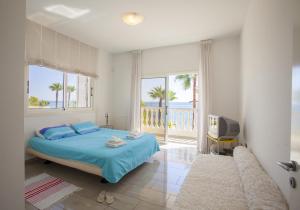 Un dormitorio con una cama y un televisor y un balcón. en Meneou Beachfront Villa Sunset, en Perivolia 62 fotos más