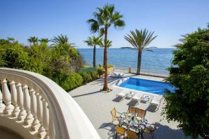 a house with a swimming pool next to the ocean at Meneou Beachfront Villa Sunset in Pervolia